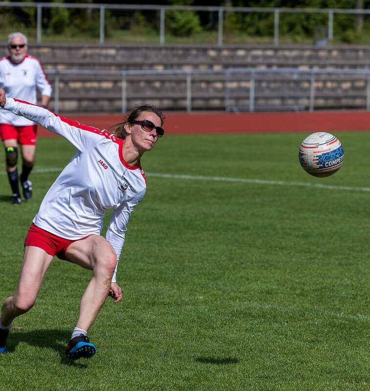 Spielerin des Walddörfer SV mit einer Sonnenbrille im weißen Trikot, läuft schlagbereit zum Faustball.